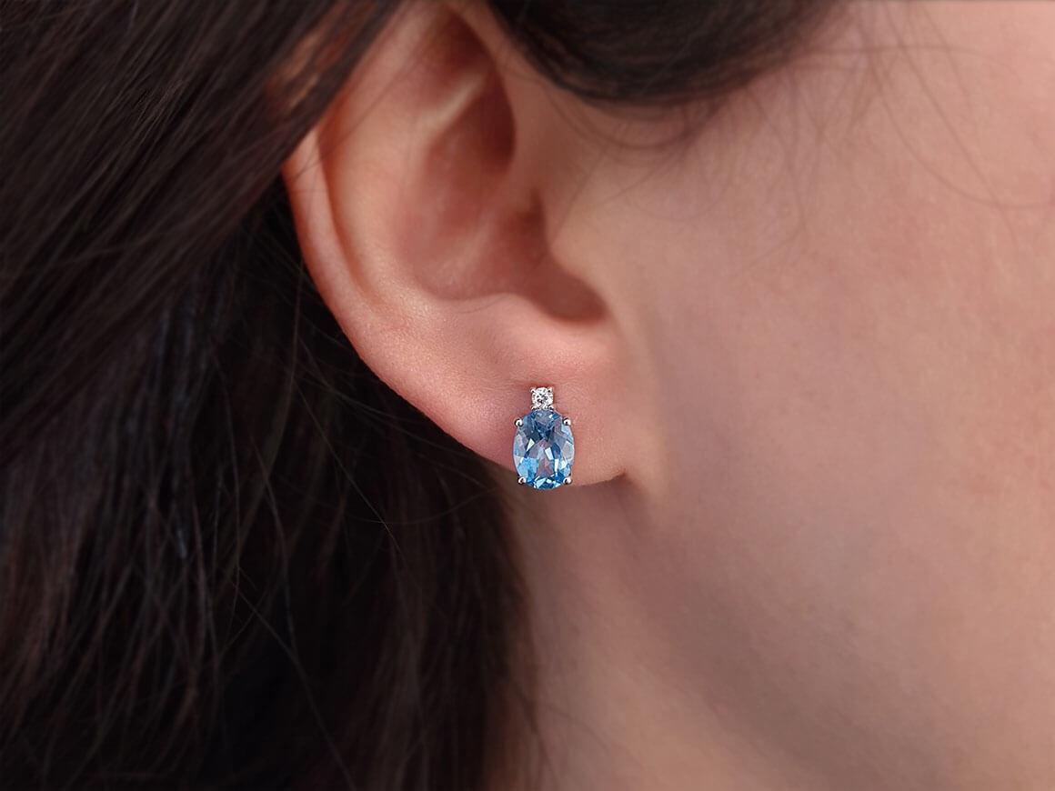 Diamond and oval blue topaz stud earrings in 333 white gold