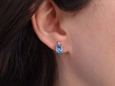Diamond and oval blue topaz stud earrings in 333 white gold