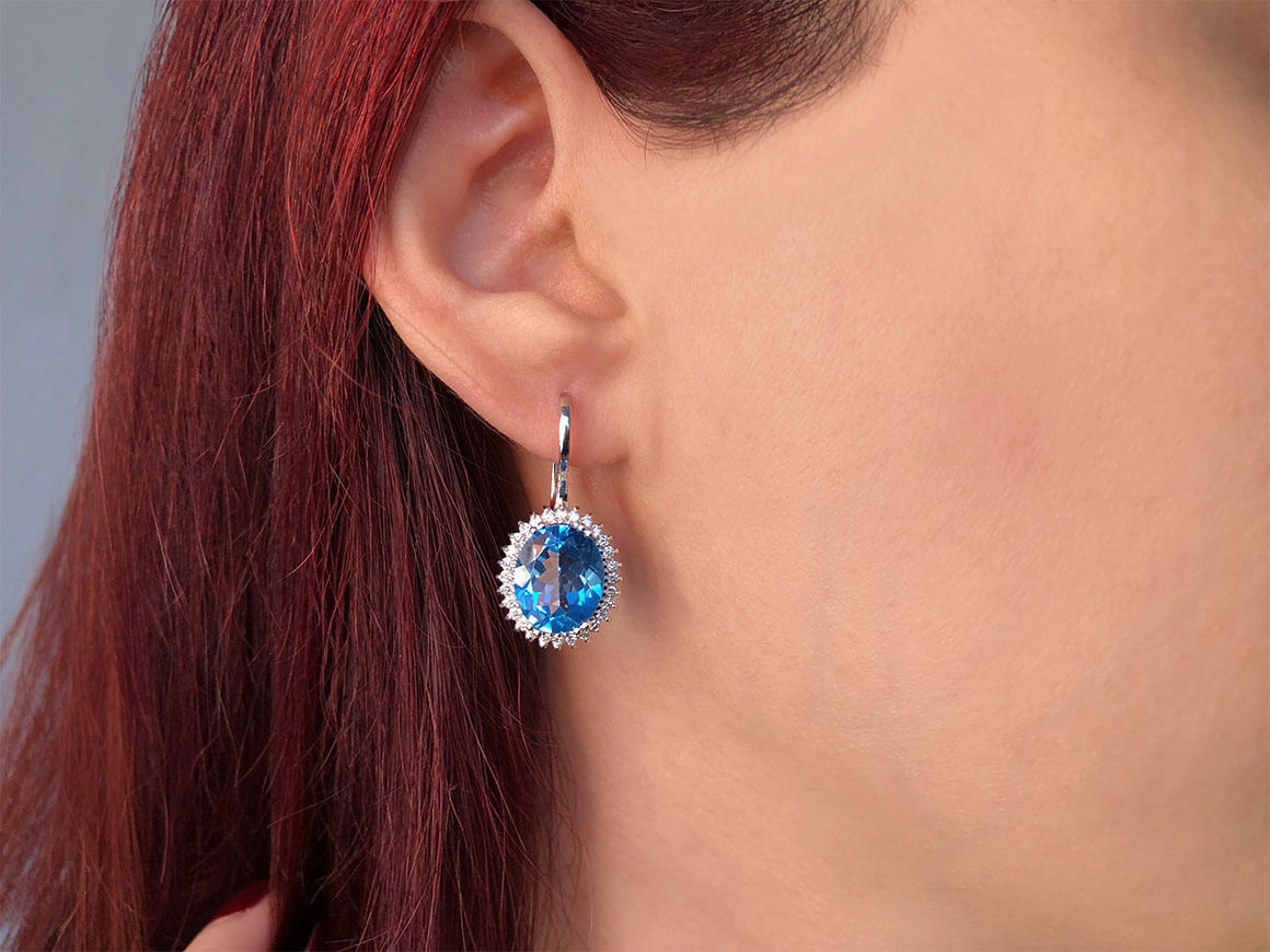 Diamond and oval blue topaz earrings in 14 carat white gold
