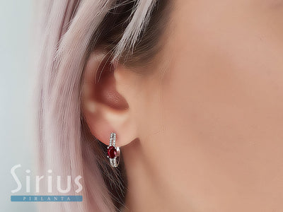 Diamond and oval ruby earrings in 14 carat white gold