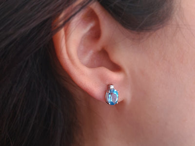 Diamond and oval blue topaz stud earrings in 333 white gold