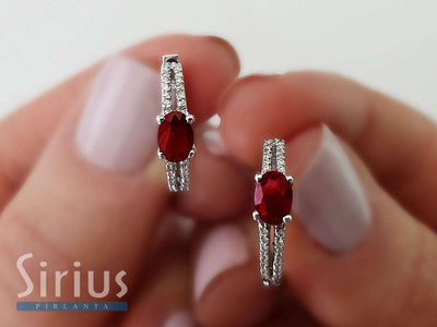 Diamond and oval ruby earrings in 14 carat white gold